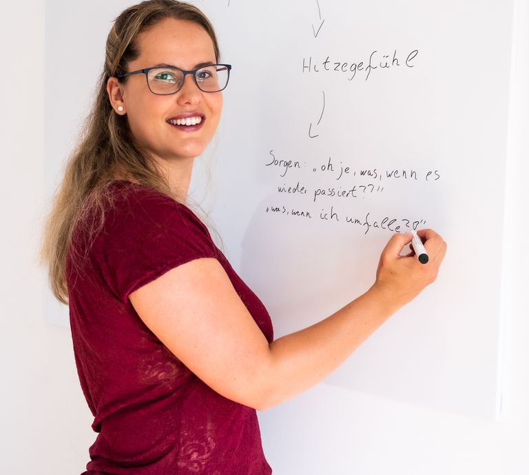 Corinna Nebel steht an einem Whiteboard und zeichnet einen Angstkreislauf auf